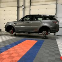 Voiture sur pont dans un centre de contrôle technique avec un revêtement de sol clipsable gris orange et bleu