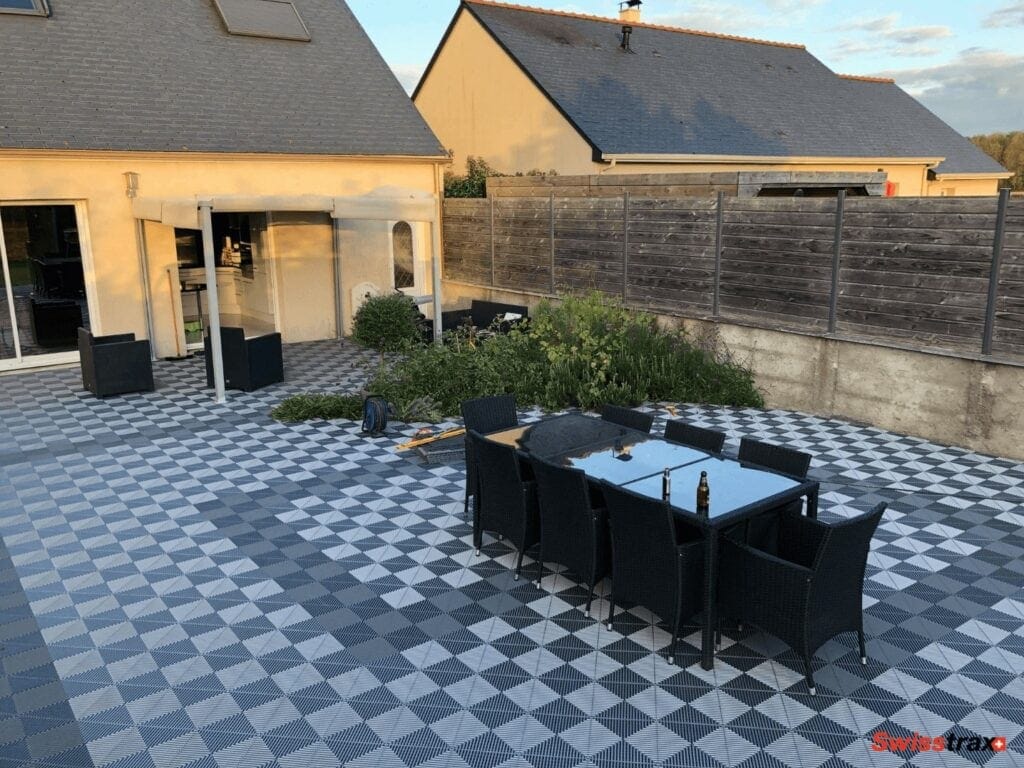 grande terrasse aménagée avec un sol clipsables en dalles effet damier en bi ton gris, salon de jardin noir