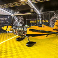 breitling booth at a trade fair with a small airplane and a floor made with yellow floor tiles