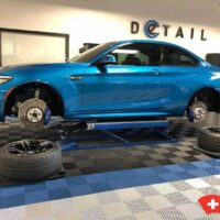 a car on a lift in a workshop with swisstrax flooring